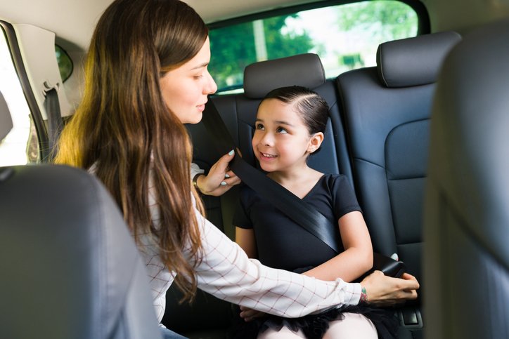 Safety is very important. Caring young mom putting the seat belt on to his little daughter to drive her to ballet dance lessons